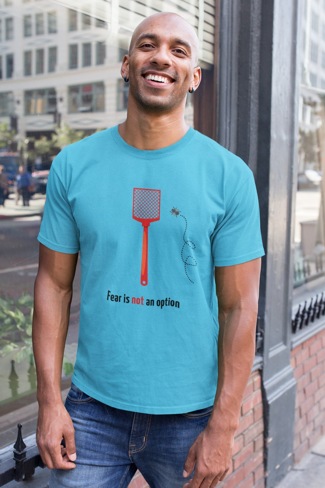"Fear is not an option". Lollig shirt met een dappere vlieg die het opneemt tegen een vliegenmepper. 100% biologisch katoen. Kleur: Aqua Blue